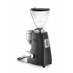 A black electric coffee grinder with a clear hopper, silver metal components, and a foot pedal, shown on a solid white background.